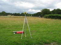 Reflector set up on radiolocated station (marked by the stake). The surveyor in the distance is using a total station to locate the station accurately